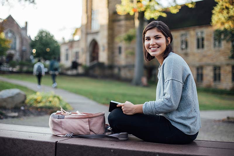 Student reading a Bible on a bench at library